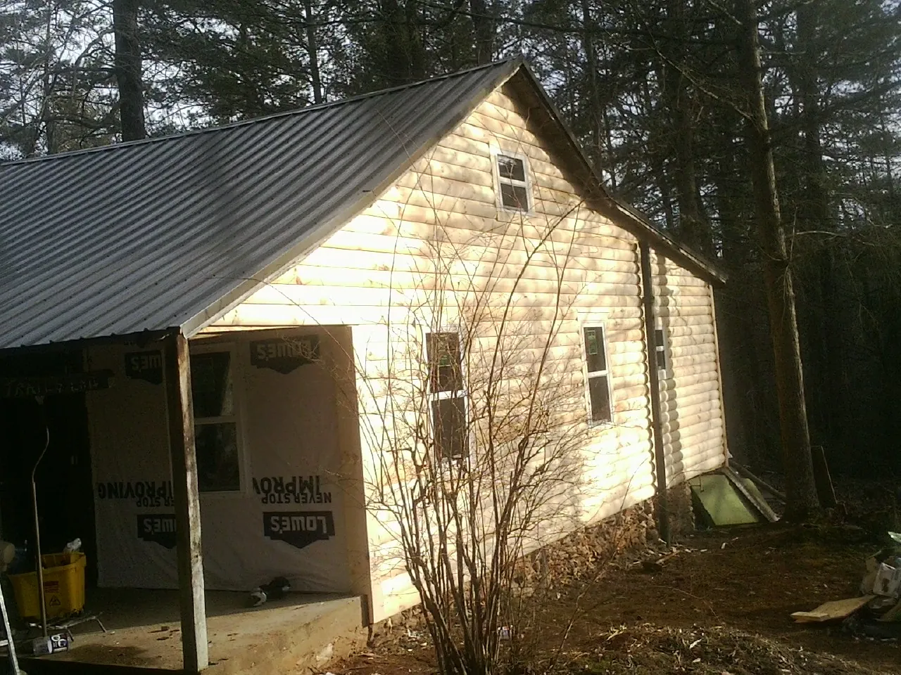 Log siding gable end under a dark metal roof edge in Good Hope