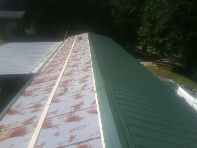Old rusted panels beside newly installed green metal roofing — Wind Damage Roof Repair by Roofing Brothers in Good Hope