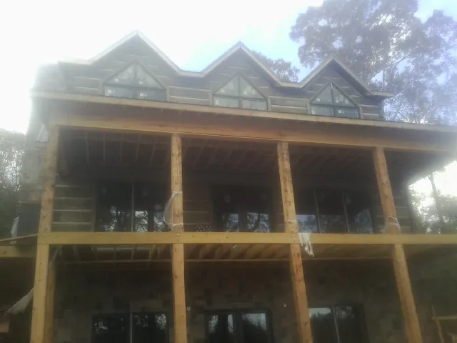 Dormers and porch framing on a large log home under construction — Roof Coating work by our crew in Good Hope