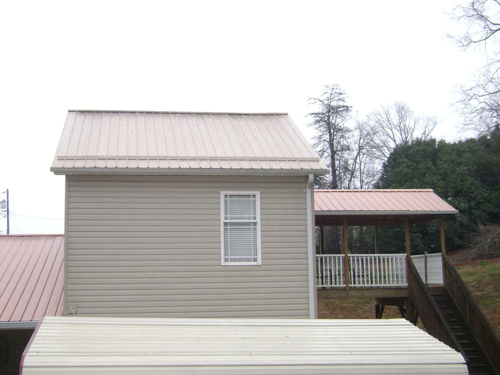 Tan metal roofs on a two story addition and attached porch, from a Roof Replacement job in Good Hope